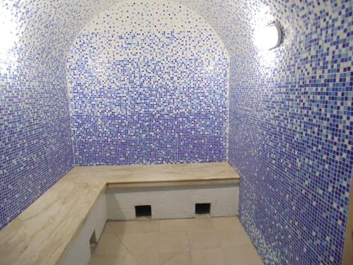 una habitación con un banco en una pared de azulejos azules en Sanatoriy Bobachevskaya Roshcha, en Tver