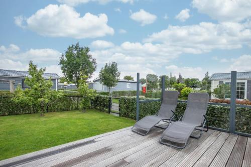 a deck with two chairs and a yard at Luxe Chalet Jara JS17 Oostkapelle in Oostkapelle
