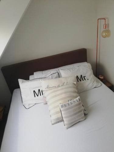 Una cama con almohadas blancas con las palabras mmr en Crèmebol, en Nieuwpoort