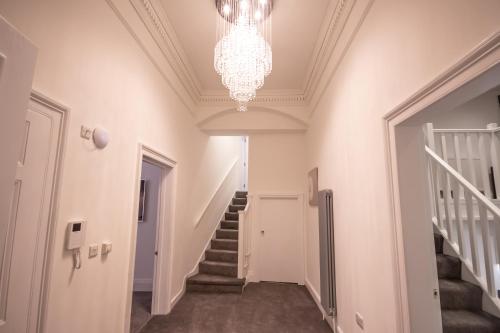 a hallway with stairs and a chandelier at The Westminster Suite in Plymouth