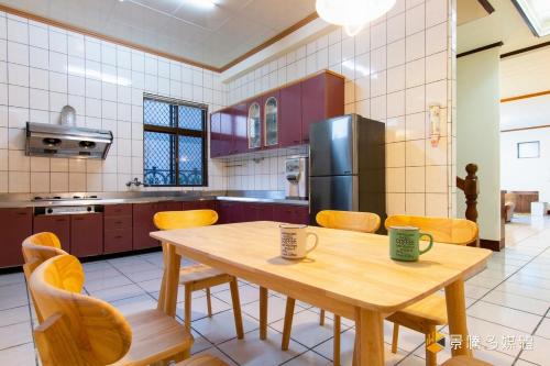 a kitchen with a wooden table and chairs and a refrigerator at Bethel Homestay in Guanshan