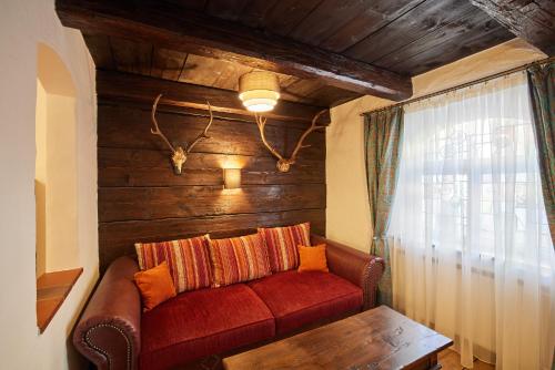a living room with a red couch and a table at Atlas Posthotel in Garmisch-Partenkirchen
