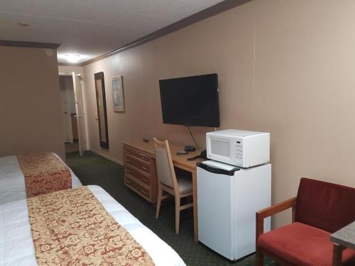 a hotel room with a bed and a desk with a microwave at Owen Sound Inn in Owen Sound