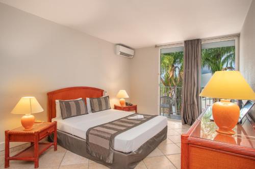 a bedroom with a bed with two lamps and a balcony at Zenitude Hôtel Résidences Le Salako in Le Gosier