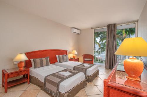 a bedroom with two beds and a large window at Zenitude Hôtel Résidences Le Salako in Le Gosier