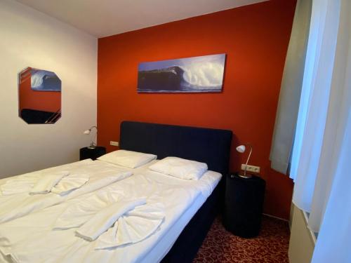 a bedroom with a white bed with an orange wall at AKZENT Waldhotel Spa Rügen in Göhren