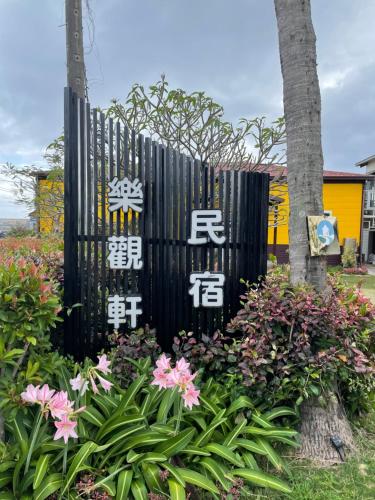 a black gate with asian writing on it next to flowers at 樂觀軒民宿 in Taitung City