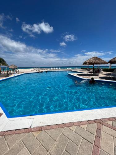a swimming pool next to the beach with umbrellas at Condominios Brisas Zona Hotelera in Cancún