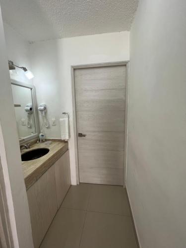 a bathroom with a door with a sink and a mirror at Condominios Brisas Zona Hotelera in Cancún