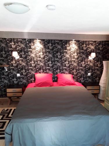 a bedroom with a large bed with red pillows and black wallpaper at Gite les Cigales in Châteauvieux