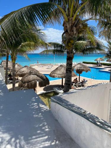 a swimming pool with palm trees and a beach at Condominios Brisas Zona Hotelera in Cancún