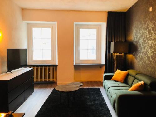a living room with a green couch and two windows at Pension Winnemuller in Cochem