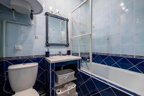 La salle de bains est pourvue de carrelage bleu, de toilettes et d'un lavabo. dans l'établissement Les Portes de la Mer, à Villers-sur-Mer