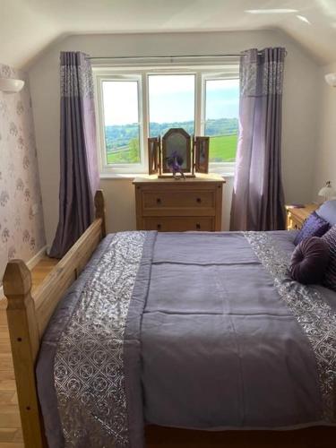 a bedroom with a large bed and a window at Orchard Cottage in Tiverton