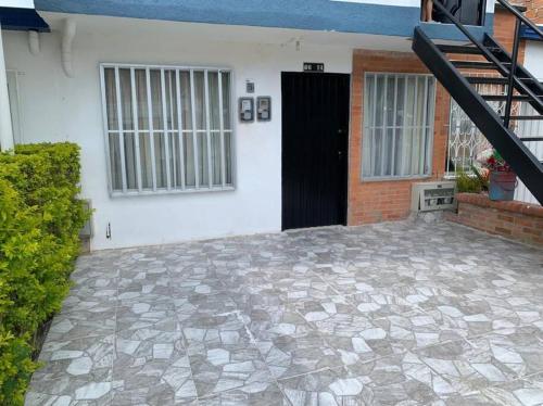 un patio frente a una casa con una puerta negra en ALOJAMIENO CERCA A UKUMARI, CONSOTA, EXPOFUTURO, en Pereira