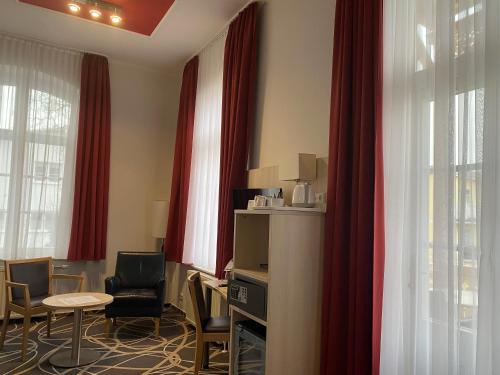 a waiting room with red curtains and a table and chairs at AKZENT Waldhotel Spa Rügen in Göhren