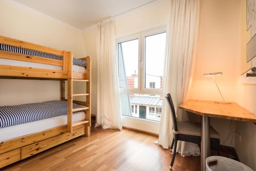 a bedroom with bunk beds and a desk and a window at Kapitänshaus Roseney in Norderney