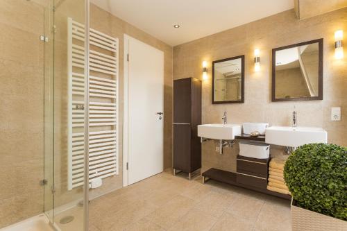 a bathroom with two sinks and two mirrors at Kapitänshaus Roseney in Norderney