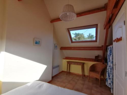 1 dormitorio con cama, mesa y ventana en Gîte de l'Hirondelle bleue, en Brech