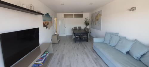 a living room with a couch and a flat screen tv at Pé n'Areia Guesthouse in Vila do Conde