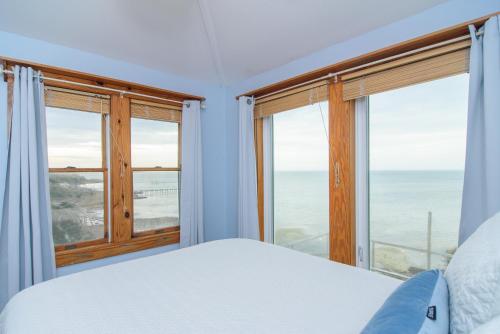 a bedroom with a bed and two large windows at The Inn on Pamlico Sound in Buxton