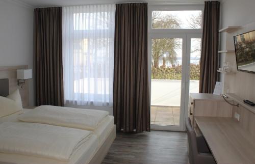 a hotel room with a bed and a large window at Hotel Sonnenklause in Travemünde
