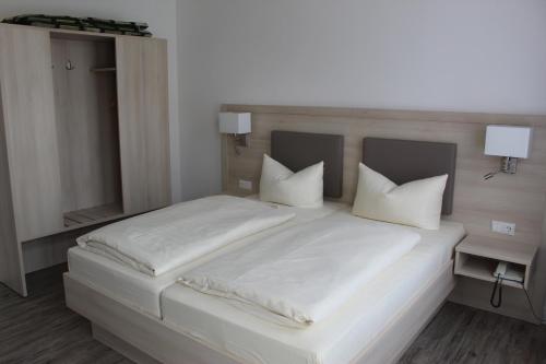 a bed with white sheets and pillows on it at Hotel Sonnenklause in Travemünde