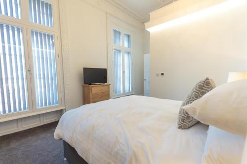a white bedroom with a bed and a television at The Windsor Suite in Plymouth