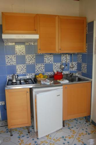 a kitchen with wooden cabinets and a sink at Villaggio Residence Nettuno in Massa Lubrense