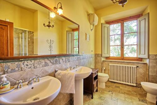 Un baño con dos lavabos y un espejo. en Casale Ambra by PosarelliVillas, en Ambra