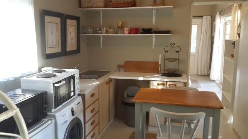 a small kitchen with a stove and a microwave at Daisy Tree Cottage in Oudtshoorn