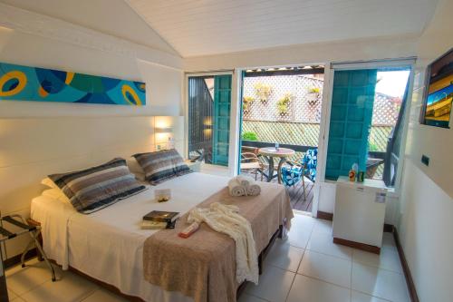 a bedroom with a bed and a balcony at Chez Pitu Praia Hotel in Búzios