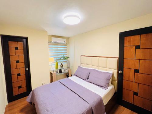 um quarto com uma cama com lençóis roxos e uma janela em Tagaytay Hampton Villa em Tagaytay