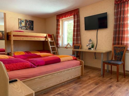 a bedroom with a bunk bed with a television and a desk at Pension Pöhlbergblick Annaberg in Annaberg-Buchholz