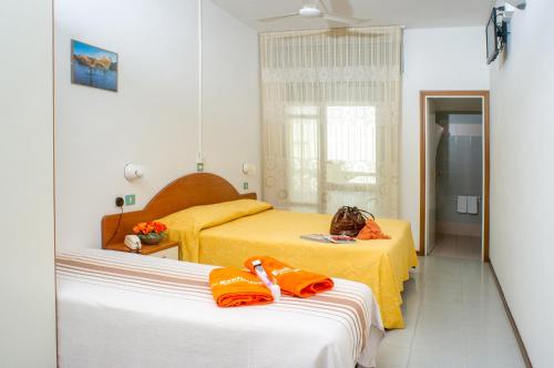 a hotel room with two beds with orange sheets at Hotel Exclusive in Riccione