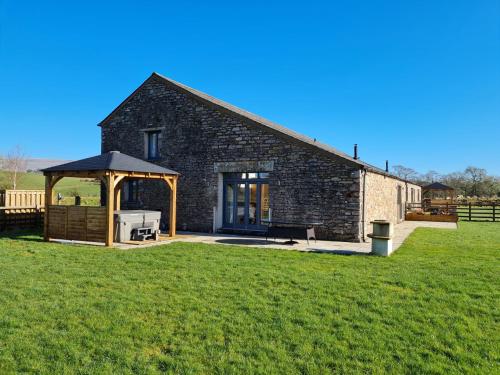 a stone house with a grill in a field at Keld Barn, Low Ploughlands Holiday Lets in Kirkby Stephen