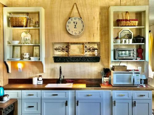 eine Küche mit weißen Schränken und einer Uhr an der Wand in der Unterkunft THE FARMHOUSE private apartments in Eufaula