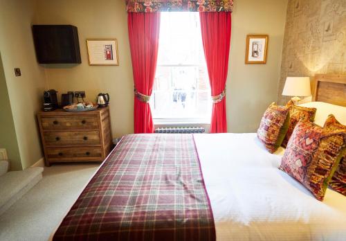 a bedroom with a bed with red curtains and a window at Wykeham Arms in Winchester