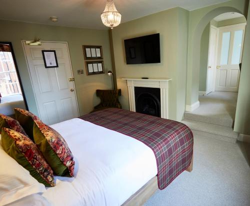 a bedroom with a white bed and a fireplace at Wykeham Arms in Winchester