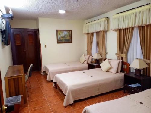 um quarto de hotel com duas camas e uma televisão em HOTEL ACHALAY em Popayán