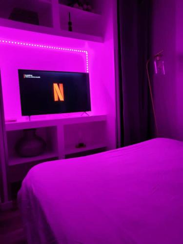 a bedroom with a bed with a computer in a pink light at Appart' Studio cooconing - Champs Elysées - NETFLIX in Maisons-Laffitte