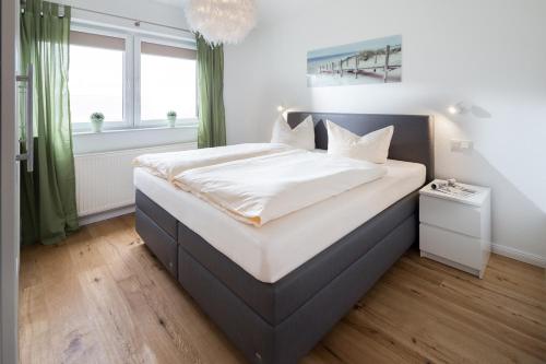 een slaapkamer met een groot bed met witte lakens bij Haus Dujardin Wohnung 13 in Norderney