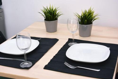 una mesa con dos platos blancos y copas de vino en Cozy Surf House, en Charneca