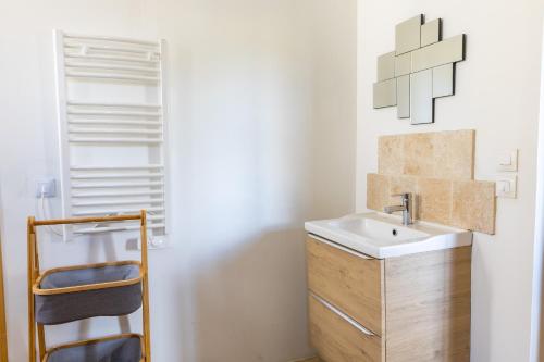 La salle de bains est pourvue d'un lavabo et d'une armoire en bois. dans l'établissement Le Domaine des Eléphants - SPA EN OPTION - 900m du Zoo, à La Cévrie