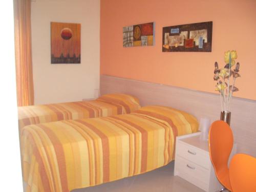 two beds in a bedroom with orange walls at B&B del centro storico *** in Rosolini