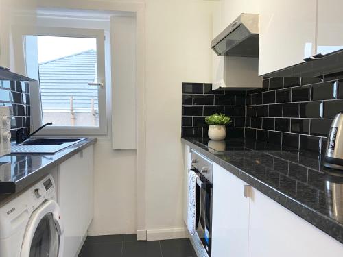 a kitchen with a washing machine and a window at Gladsmuir House in Glasgow