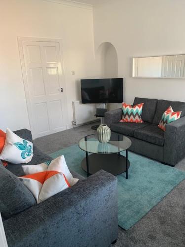 a living room with two couches and a table at Gladsmuir House in Glasgow