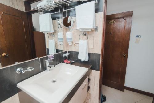 een badkamer met een witte wastafel en een spiegel bij HOTEL ACHALAY in Popayan