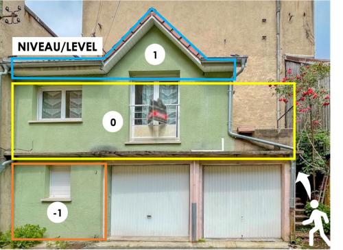 a house with three garage doors and a person in the window at Maisonnette Le Faubourg - CENTRE VILLE, TERRASSE ET NETFLIX in Belfort