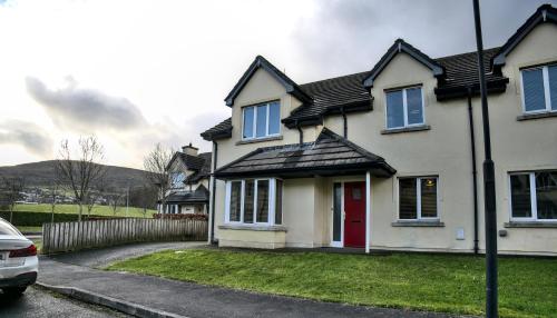 a white house with a red door and a fence at Village Lodge - Carlingford in Carlingford